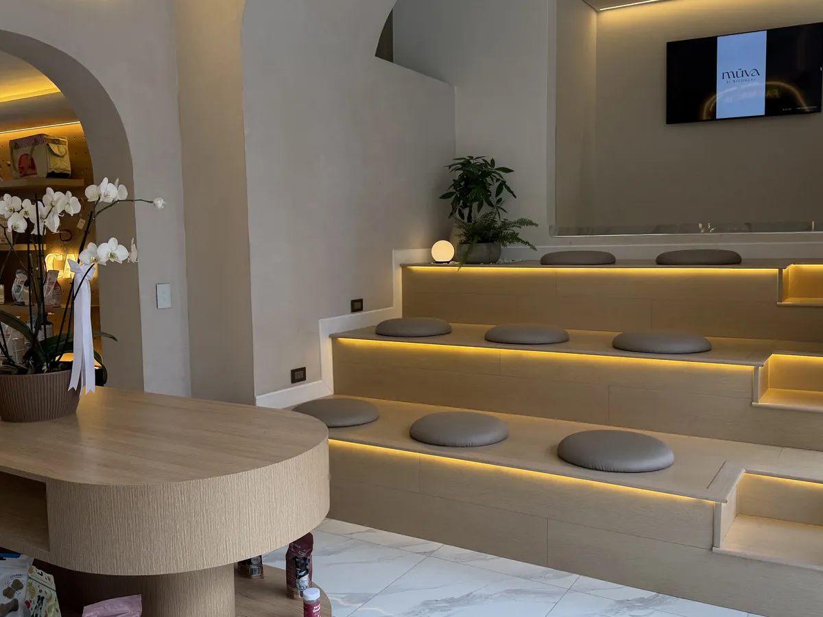 Sala de espera de MÜVA con gradas de madera iluminadas y cojines grises